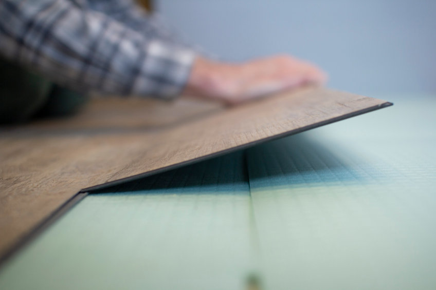 Vinyl laminate. Laying of the floor covering. A worker installing a new vinyl tile on the floor